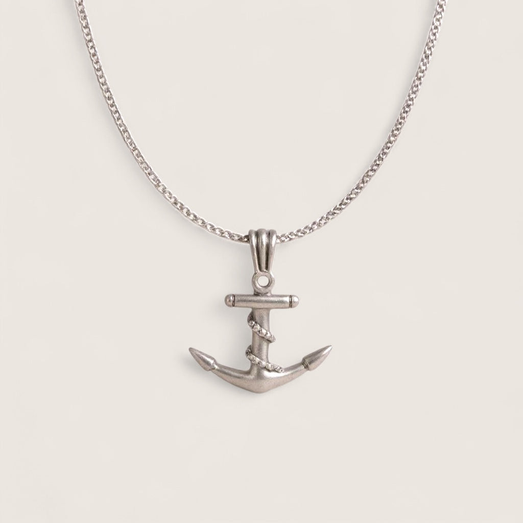Silver anchor necklace on a light gray background