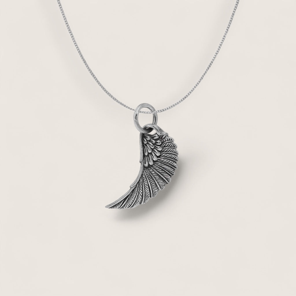 Silver wing-shaped pendant on a chain against a light gray background