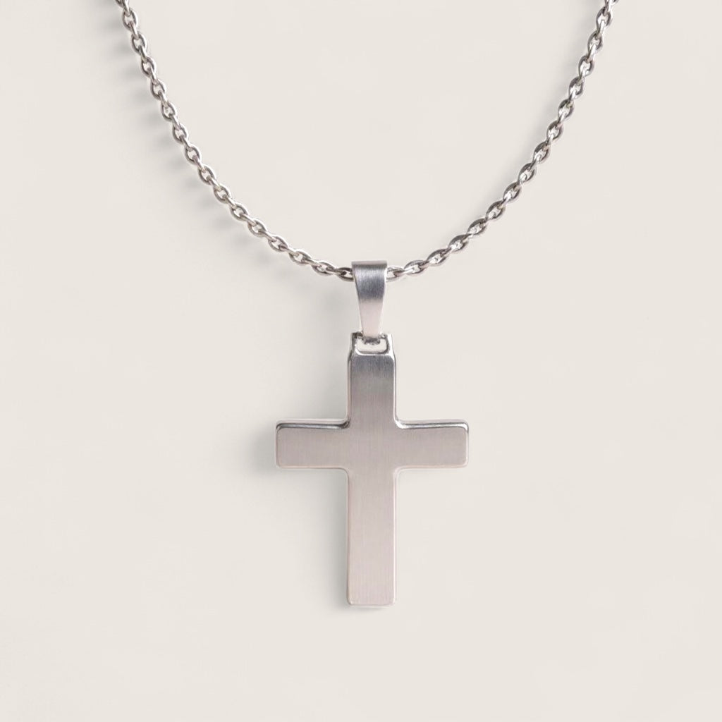 Silver cross pendant on a chain against a light gray background