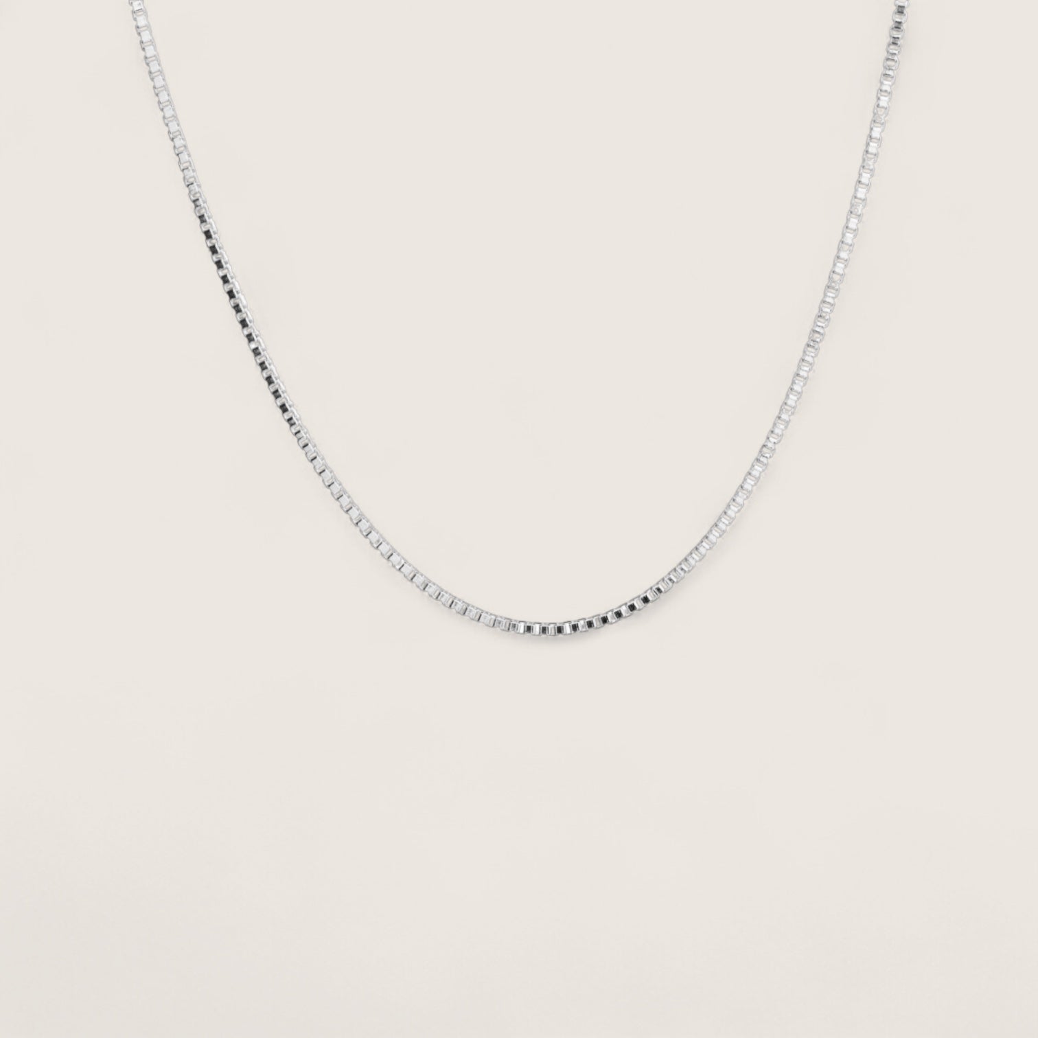 Silver chain necklace on a light beige background