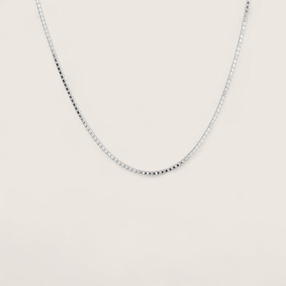 Silver chain necklace on a light beige background