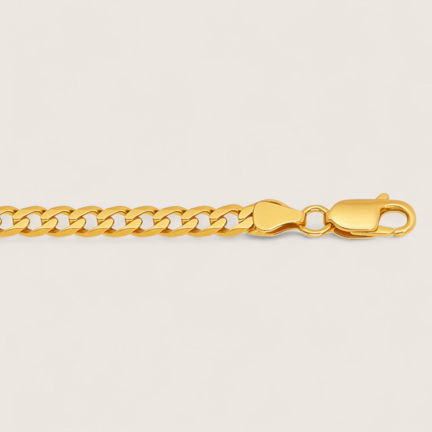 Gold chain bracelet on a light beige background