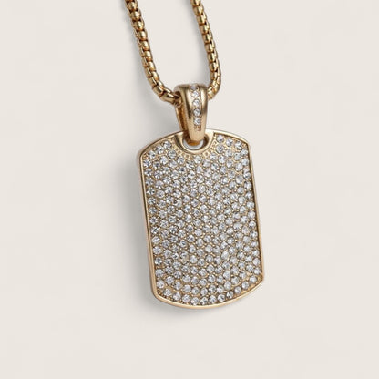 Gold necklace with a diamond-encrusted dog tag on a beige background