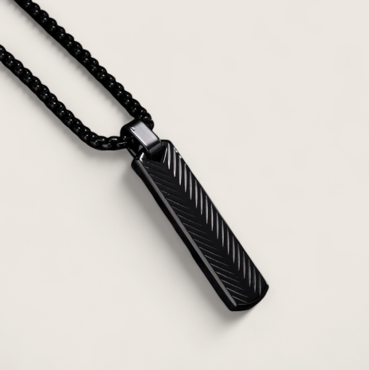 The Axis – Steel Bar Necklace-Elevate your look with the Axis Pendant. Sleek steel bar with chevron-textured detail in polished silver or matte black. Minimal, modern style. Shop now.