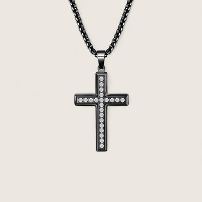 Black cross pendant necklace with clear stones on a beige background