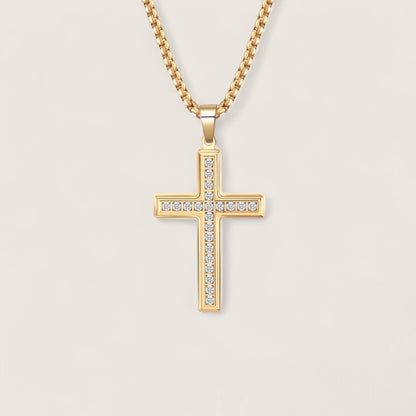 Gold cross necklace with clear stones on a light beige background