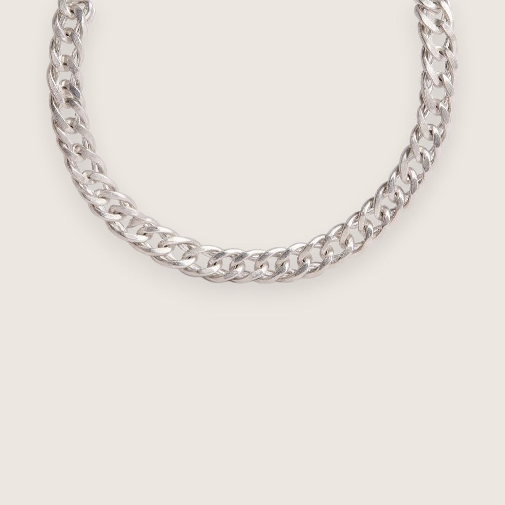 Silver chain necklace on a light gray background