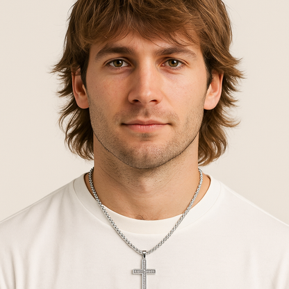 Man wearing a silver cross necklace against a plain background