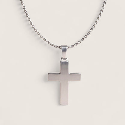 Silver cross pendant on a chain against a light gray background
