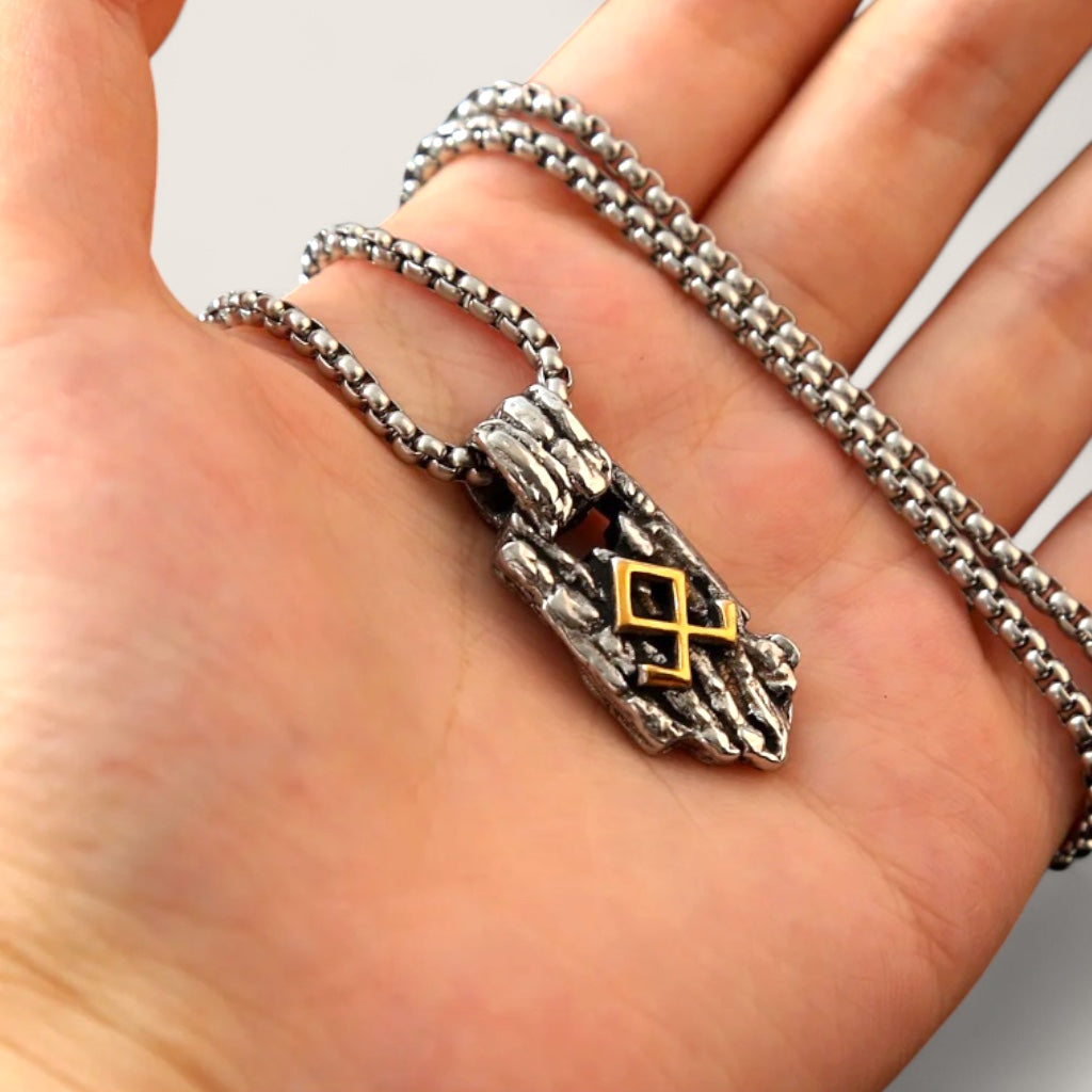 Silver necklace with a pendant featuring a symbol held in a hand against a neutral background